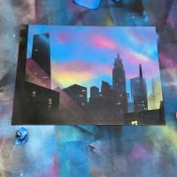 Spray paint on canvas painting of a city at dusk